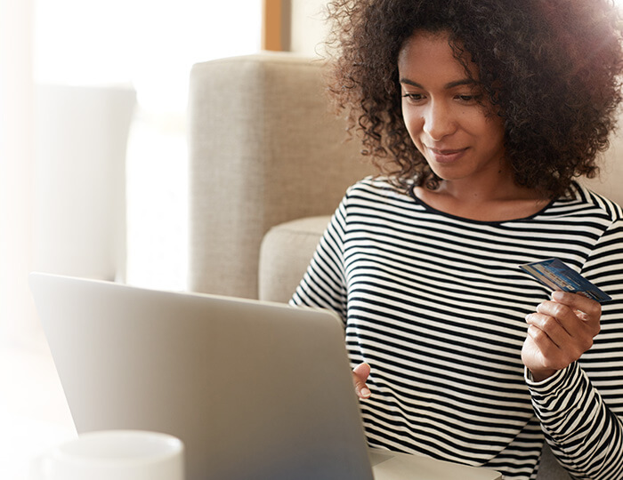 woman holding credit card and using computer