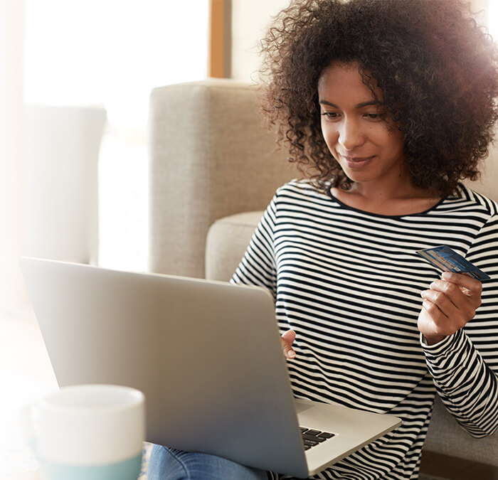 woman holding credit card and using computer